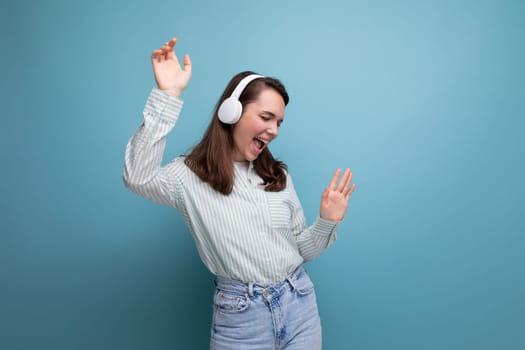 dancing 25 year old brunette woman in a shirt and jeans enjoys music in headphones.