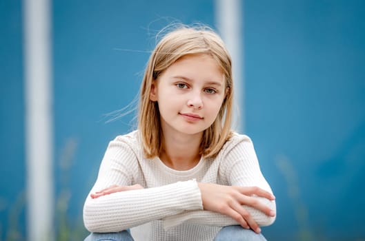 Cute preteen gitl with blond hair portrait. Pretty child kid model sitting and looking at camera