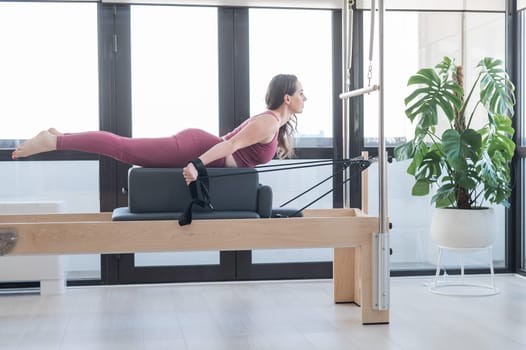 Woman doing pilates exercise on cadillac reformer machine