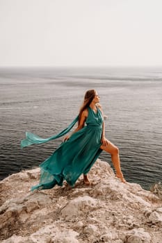 Woman sea green dress. Side view a happy woman with long hair in a long mint dress posing on a beach with calm sea bokeh lights on sunny day. Girl on the nature on blue sky background