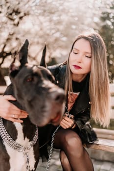 A woman walks with her Great Dane in an urban setting, enjoying the outdoors and the company of her dog