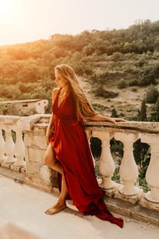 Woman red dress. Summer lifestyle of a happy woman posing near a fence with balusters over the sea