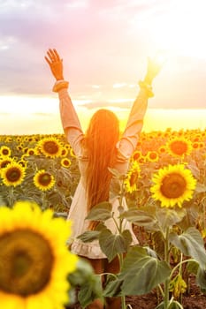 Woman sunflower field. Happy girl in blue dress and straw hat posing in a vast field of sunflowers at sunset. Summer time