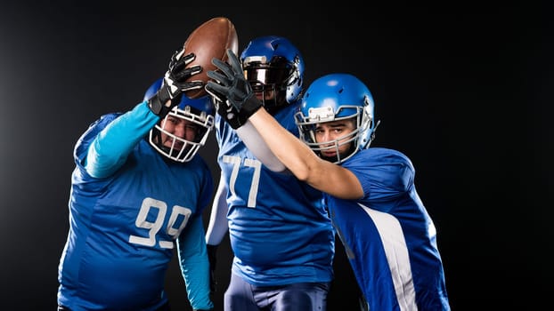 Three American football players raising their hands up holding the ball on a black background
