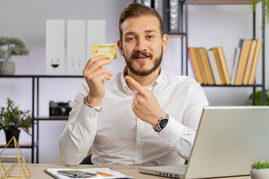 Business man show plastic credit bank card advertising transferring money cashless, purchases online shopping, sale discount, internet order delivery, booking. Freelancer guy talking looking at camera