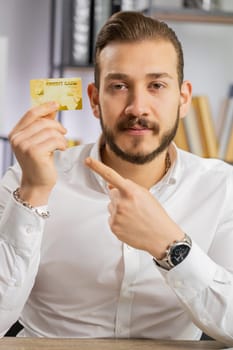 Business man showing plastic credit bank card advertising transferring money cashless, purchases online shopping, sale discount, internet order delivery purchase. Freelancer guy at office. Vertical