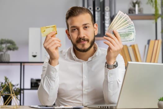 Business man show plastic credit bank card and money dollar cash advertising transferring cashless, purchases online shopping, sale discount, internet order delivery. Guy talking looking at camera