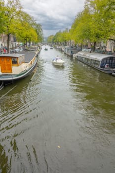 Netherlands. Cloudy summer day in Amsterdam. Houseboats and boats on the canal