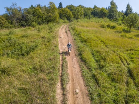 Enduro athlete on the forest path on a sunny summer day. Aerial drone view