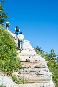 Tourists climb the stairs to the top of the mountain. Norway hiking path in mountains. Lofoten, Reinebringen. hiking tourist climbing Reinebringen stone stairs to mountain peak.