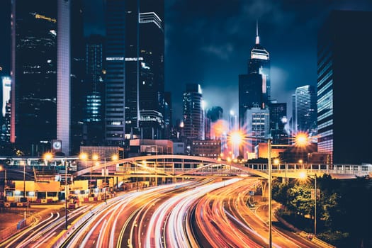 Street traffic in Hong Kong at night. Office skyscraper buildings and busy traffic on highway road with blurred cars light trails. Hong Kong, China