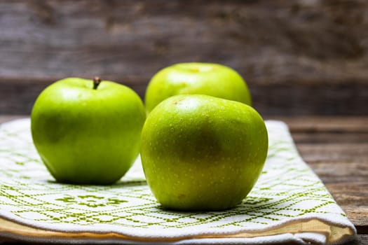 Detail on ripe green apples on wooden table.