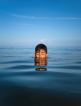 Relaxation and healthy lifestyle. Young boy teenager bathes in the sea.