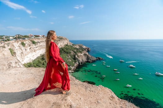 Red Dress Woman sea Cliff. A beautiful woman in a red dress and white swimsuit poses on a cliff overlooking the sea on a sunny day. Boats and yachts dot the background