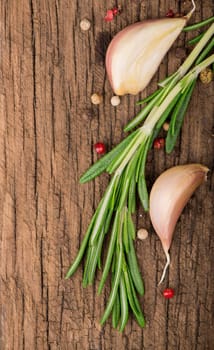 Dark culinary background with garlic, rosemary, bay leaves, pepper and some cloves pictured on it