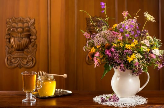 bouquet of wildflowers, honey and tea on the old board.