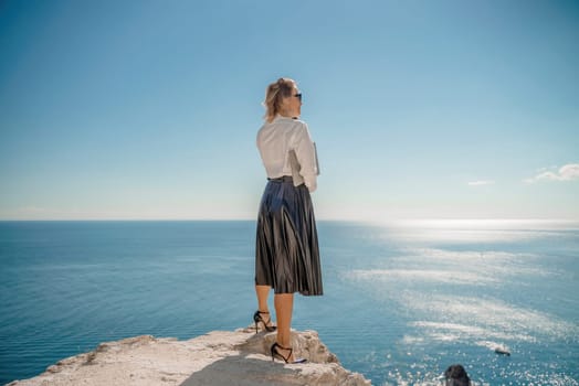 Freelance women sea working on a computer. Pretty middle aged woman with computer and phone outdoors with beautiful sea view. The concept of remote work