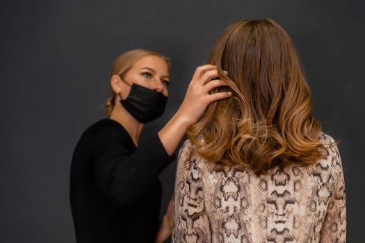 Women salon hairstyle. Hairdresser uses hairspray on client's hair in salon, Portrait of two beautiful women.