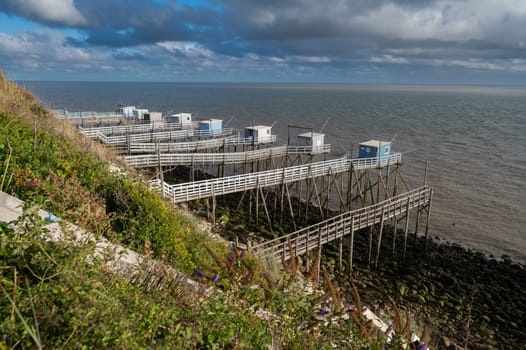 Traditional fisherman's wooden hut at the bottom of the limestone cliff in the estuary of Gironde, Talmont-sur-Gironde, France. High quality photo