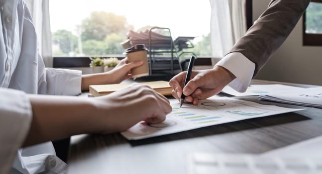 Two Asian business women Discussing Financial reports, analytical concepts, planning and financial statistics and investment markets at the office.