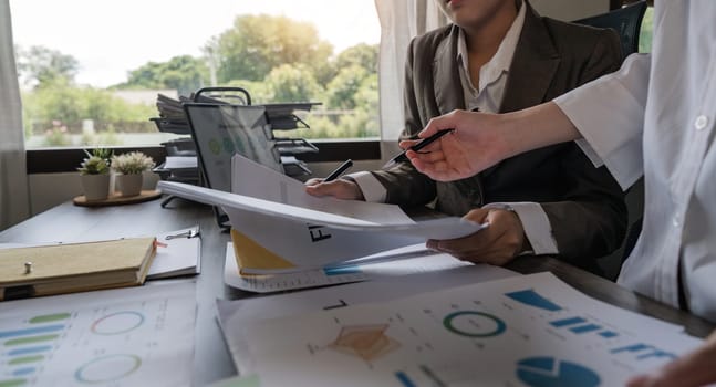 Two Asian business women Discussing Financial reports, analytical concepts, planning and financial statistics and investment markets at the office.