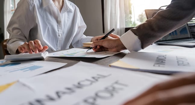 Teamwork of business two colleagues analysis with financial data and marketing report graph, Young business woman two co worker discussing for calculating financial document with calculator.