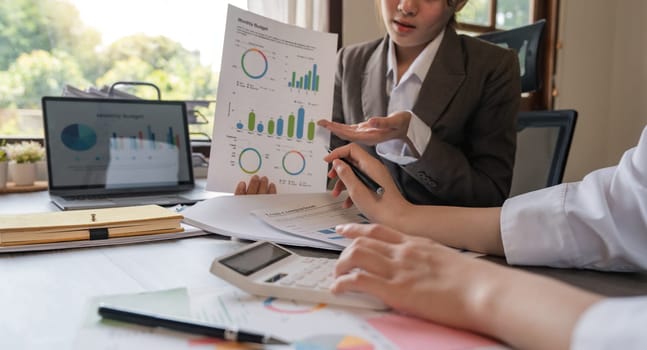 Teamwork of business two colleagues analysis with financial data and marketing report graph, Young business woman two co worker discussing for calculating financial document with calculator.