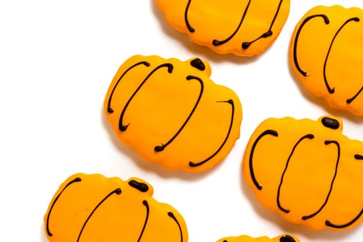 Sugar cookies with orange icing shaped like a pumpkin.