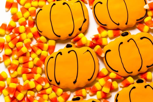 Sugar cookies with orange icing shaped like a pumpkin.