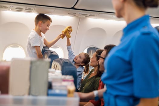 Two happy kids playing with a toy during flight. Family traveling together by plane. Vacation, travel, airline, service concept