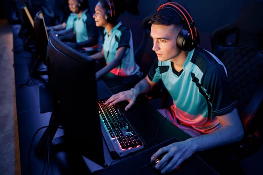 Young esports player concentrated on game wearing wired headset while playing online multiplayer game in cyber club