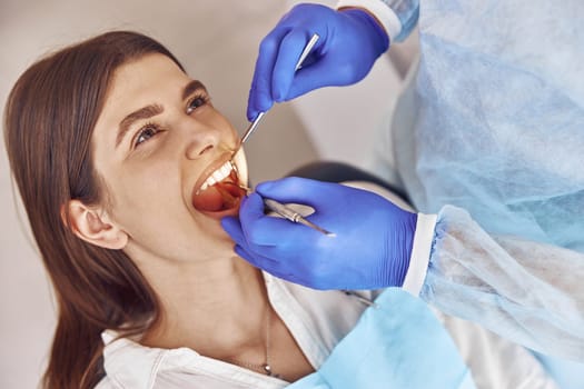 Professional doctor is doing tooth surgery to happy caucasian woman in modern dental cabinet