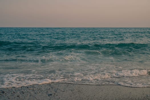 Waves of Mediterranean Sea rolling to the sandy Turkish beach. Beautiful Turkish evening.