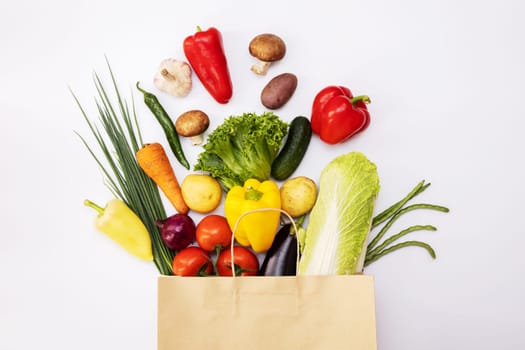 Fresh vegetables in eco friendly paper bag on white background, top view. Food delivery. Grocery shopping. Healthy eating concept.