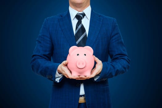 Businessman in suit is holding piggy bank. Businessman holding pig money box. Finance Savings concept