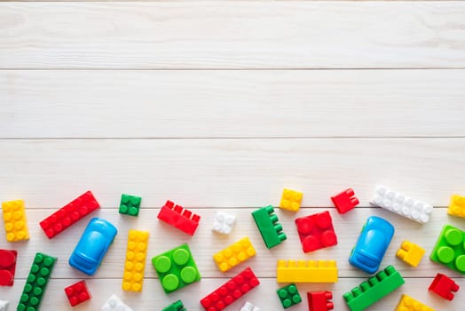 Colorful plastic toy blocks. Colorful plastic toy blocks on white wooden background with copy space. Top view. Baby background.