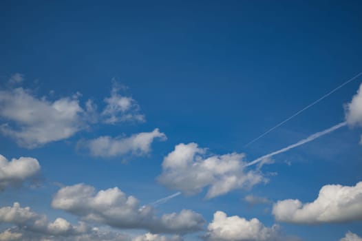 Blue sky mostly filled with white fluffy clouds. The clouds are in various shapes and sizes highlighted by a darker blue color which helps them to stand out and adds depth to the image