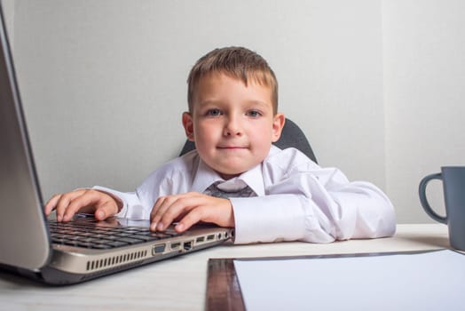 Young business boy is working in the office. A child disguised as a businessman. Funny kids.