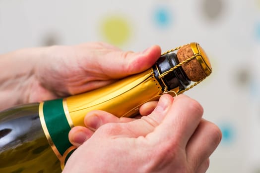 Mans hands are opening the bottle of champagne alcohol and wine drink on party celebration event. A man is opening the champagne bottle.