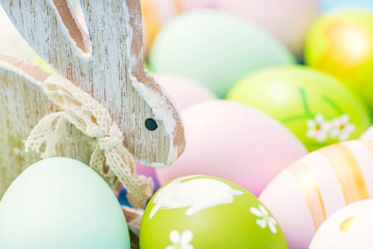 Colorful Easter eggs and wooden rabbit. Cute rabbit among Easter eggs.