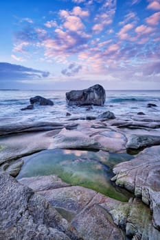 Rocks on beach of fjord of Norwegian sea in winteron sunset. Utakliev beach, Lofoten islands, Norway