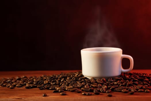 Warm cup of coffee and coffee beans on dark background. Coffee cup and coffee beans on wooden table.