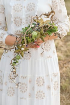 The bride holds an unusual braided wedding bouquet in her hands.