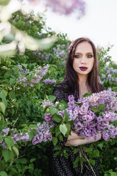 A fashionable girl with dark hair, a spring portrait in lilac tones in summer. Bright professional makeup