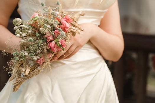 The bride holds her wedding bouquet in her hands.