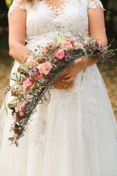 The bride holds her wedding bouquet in her hands.