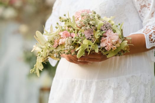 The bride holds her wedding bouquet in her hands.