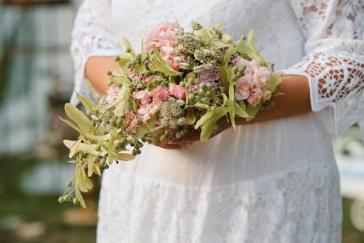 The bride holds her wedding bouquet in her hands.