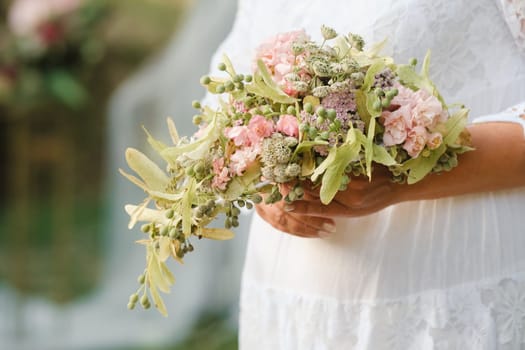 The bride holds her wedding bouquet in her hands.