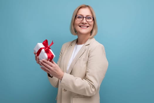 mature woman in a jacket received a gift for the holiday on a studio background with copy space.